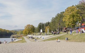 A peaceful park scene with riverside path, trees, and playground, perfect for a family outing.